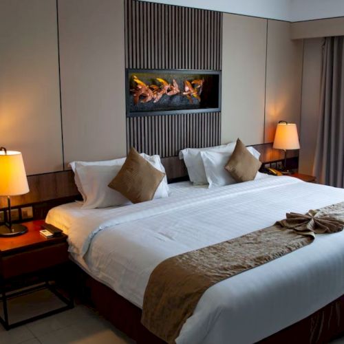 A cozy hotel room with a large bed, elegant decor, two lamps, and a small seating area by the window completes the look.