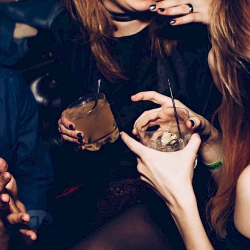 People are socializing with drinks in hand, enjoying a lively atmosphere together.