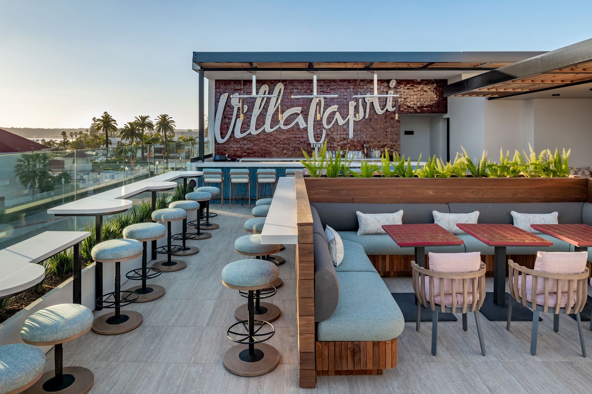 Rooftop terrace with modern seating, plants, and a wall with "Villa Capri" sign. Offers views and seating arrangements for groups.