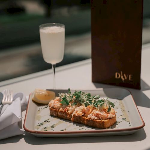 A plate of food topped with greens, a drink, and a menu on a table are shown in the image.