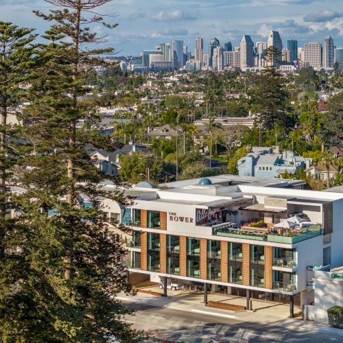 The image shows a building labeled "The Monsaraz," with trees, residential areas, and a city skyline in the background.