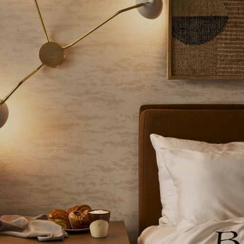 A cozy bedroom scene with a wooden headboard, soft lighting, and a few round wall lamps above a nightstand.