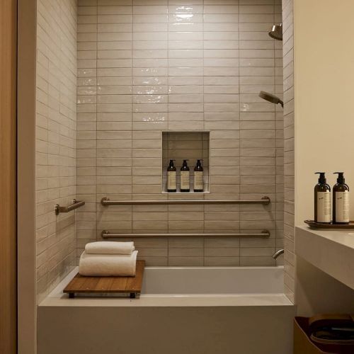 A cozy, tiled walk‑in shower with a built‑in bench, a recessed shelf, a small faucet and showerhead, and a simple, neutral color palette.