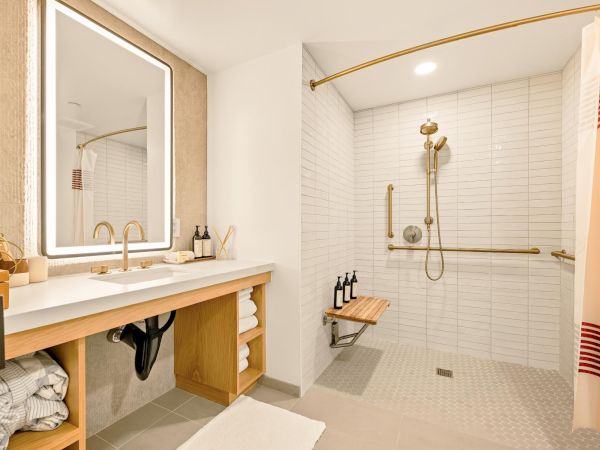 A modern bathroom with a glass shower, white subway tiles, a wooden vanity, and a large backlit mirror; plush towels and spa-like accents.