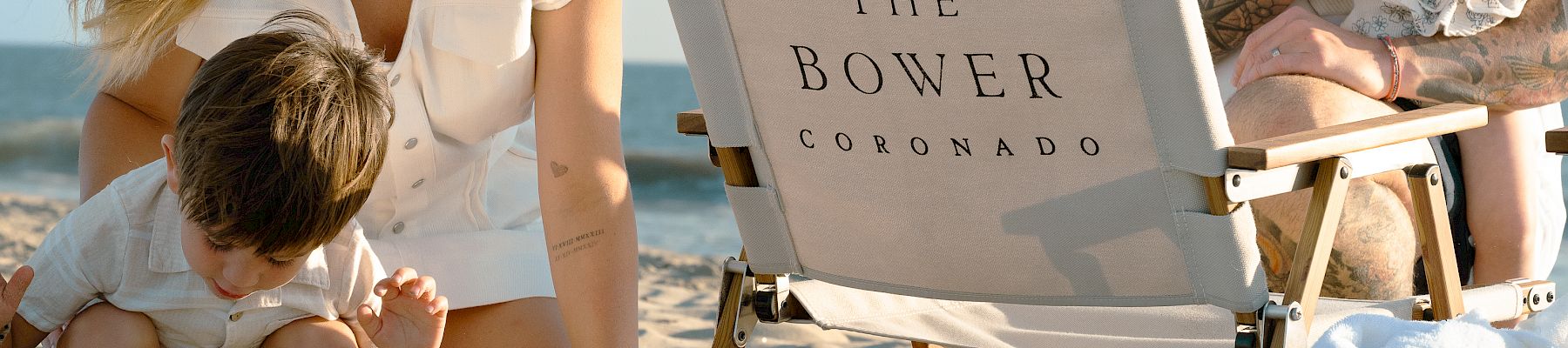 A sunny beach family lounges on sand while parents and kids sit by a “The Bower Coronado” chair, smiling.
